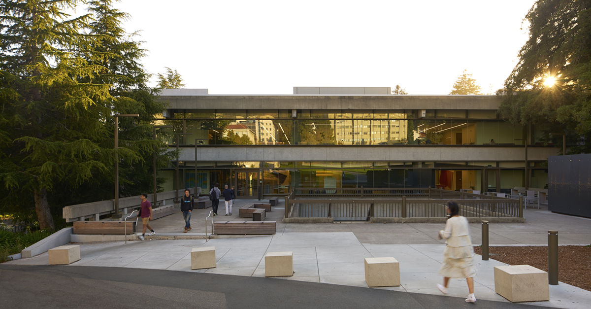 Students walk toward Moffitt Library at sunset