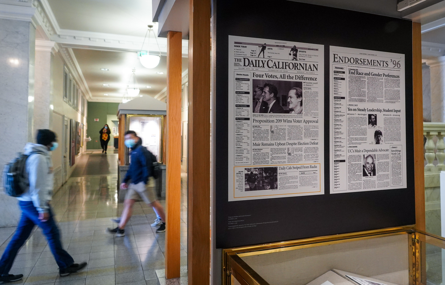 Visitors walk by the Daily Cal exhibit in Doe Library