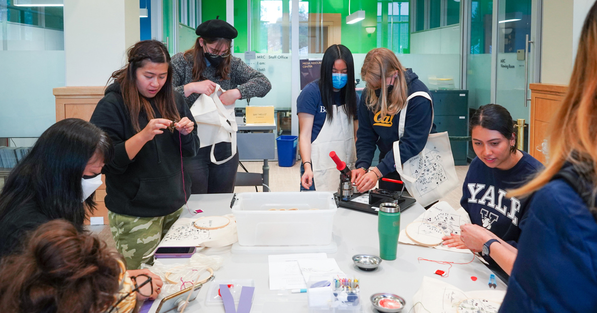 Students embroider and work on projects around a table