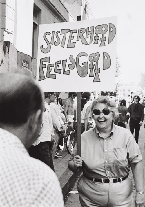 A woman holds a sign that says sisterhood feels good